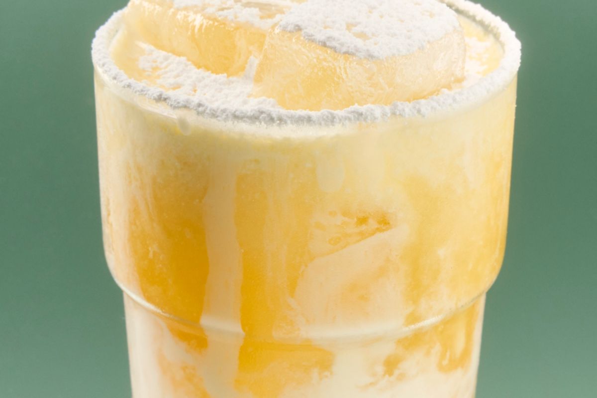 The Peach Whiskey Sour is finished with icing sugar on top 