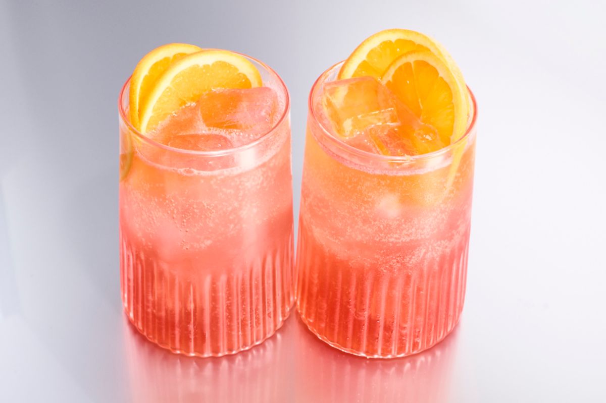 Two tall glasses of the Rome with a view, garnished with orange wheels
