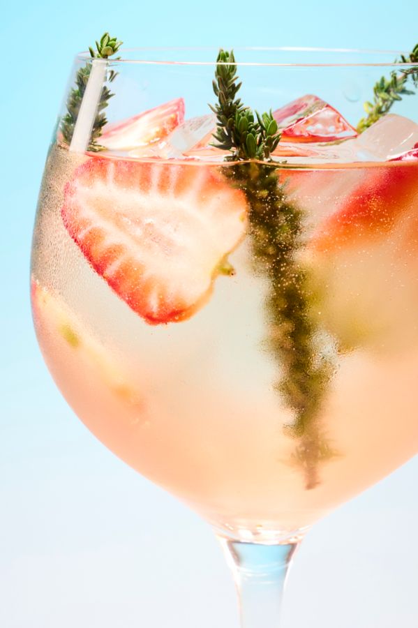The Rosé Spritzer in a wine glass with strawberries and thyme to garnish