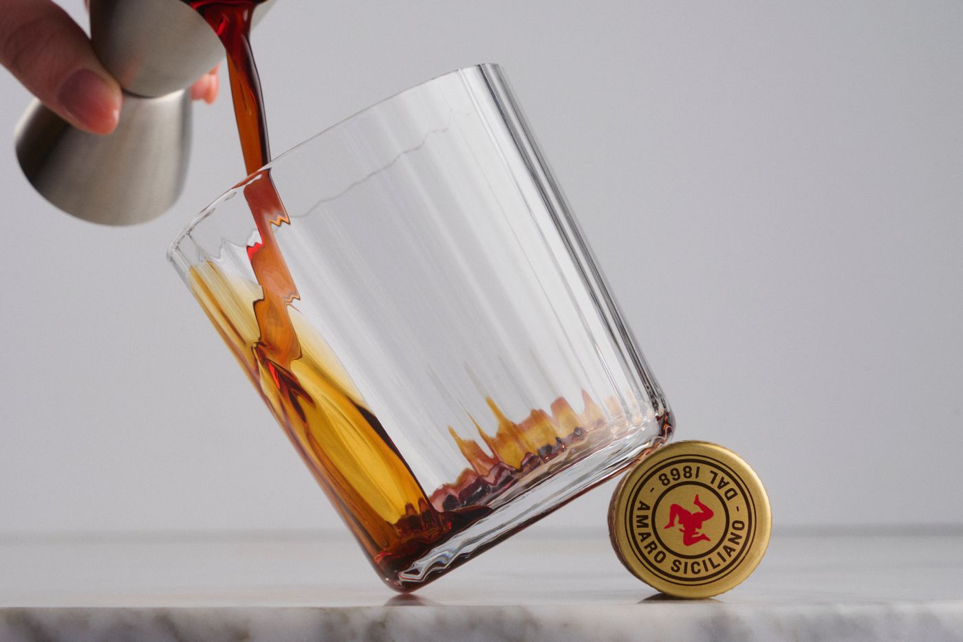 Pouring a nip of amaro into a glass