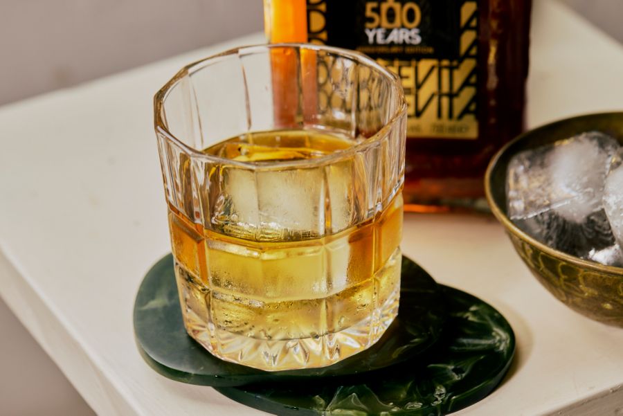 A glass of Disaronno on a table with a limited edition bottle