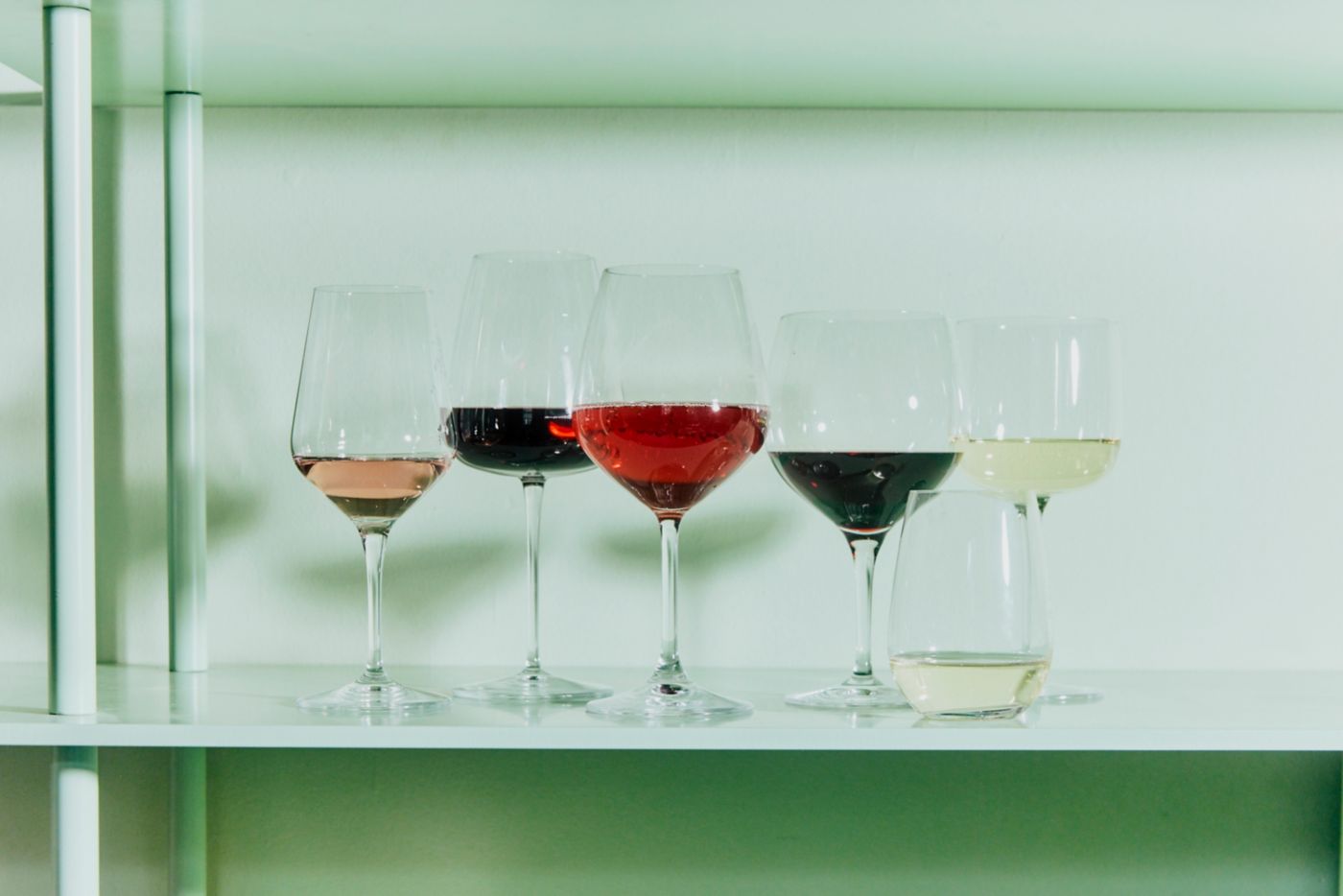 Various wine glasses with different wines on a shelf