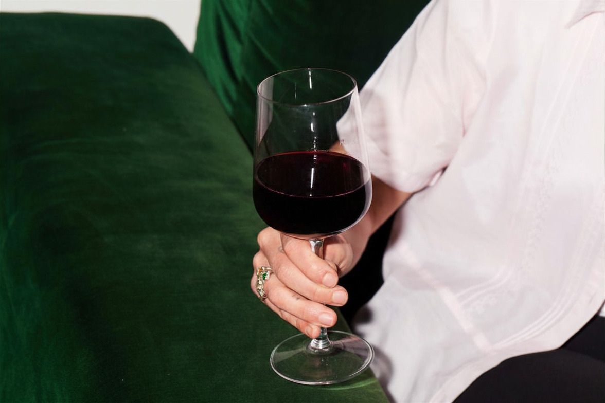 A lady sitting on a couch, holding a glass of red wine